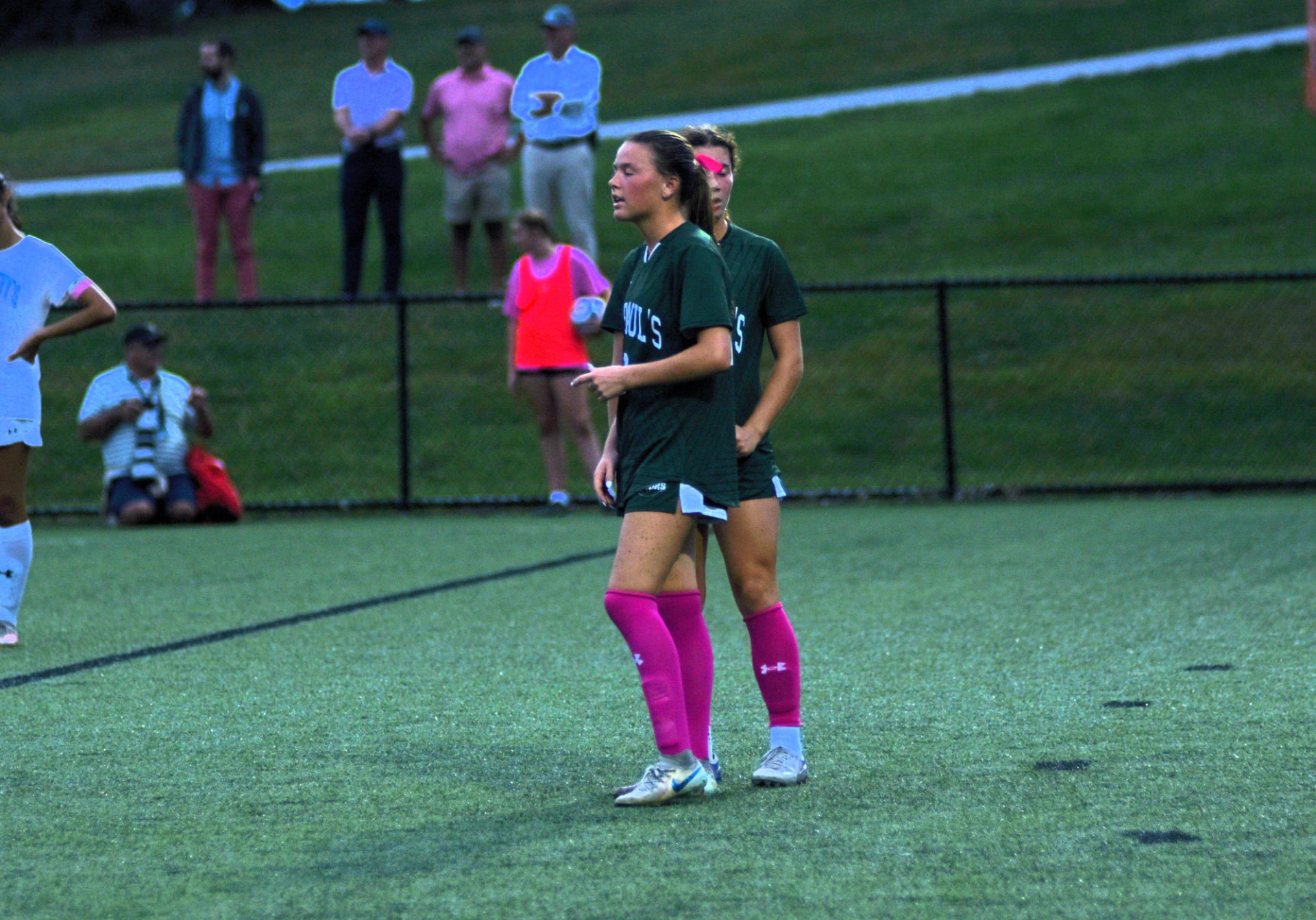 Two Gators players in green and pink set up on the field