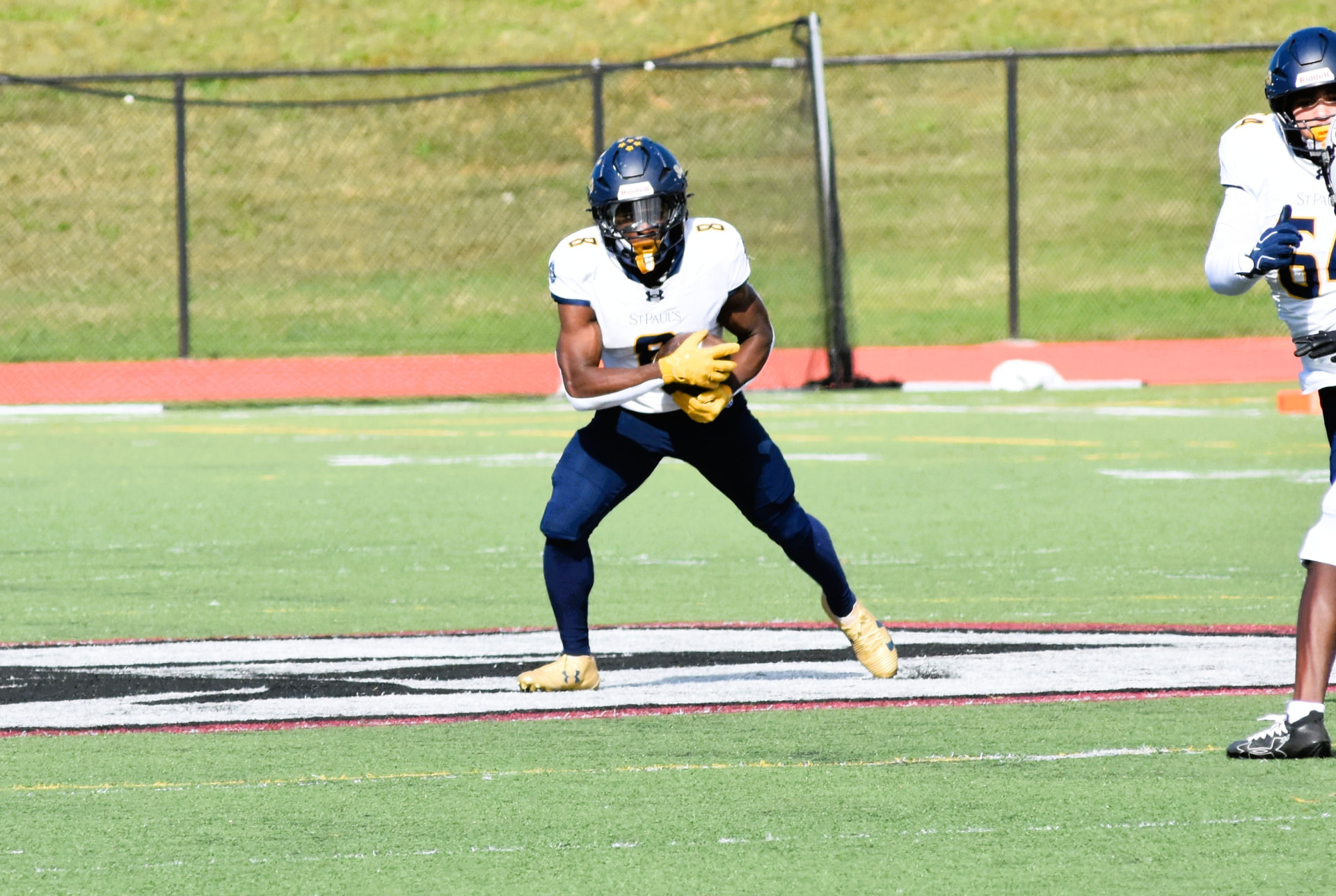 A Crusader holds the football in gold gloves and prepares to run